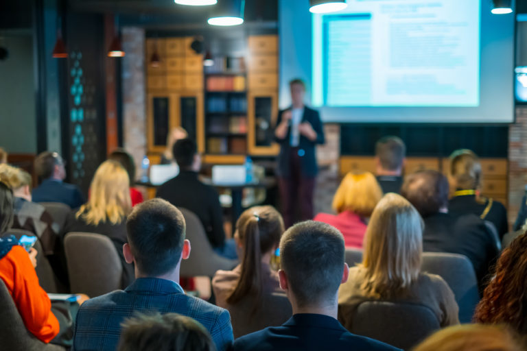 An audience listens to a speaker giving a workshop or presentation on intercultural topics