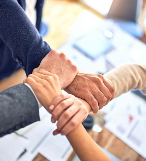 People are holding hands in a Team Coaching to show a Team bond